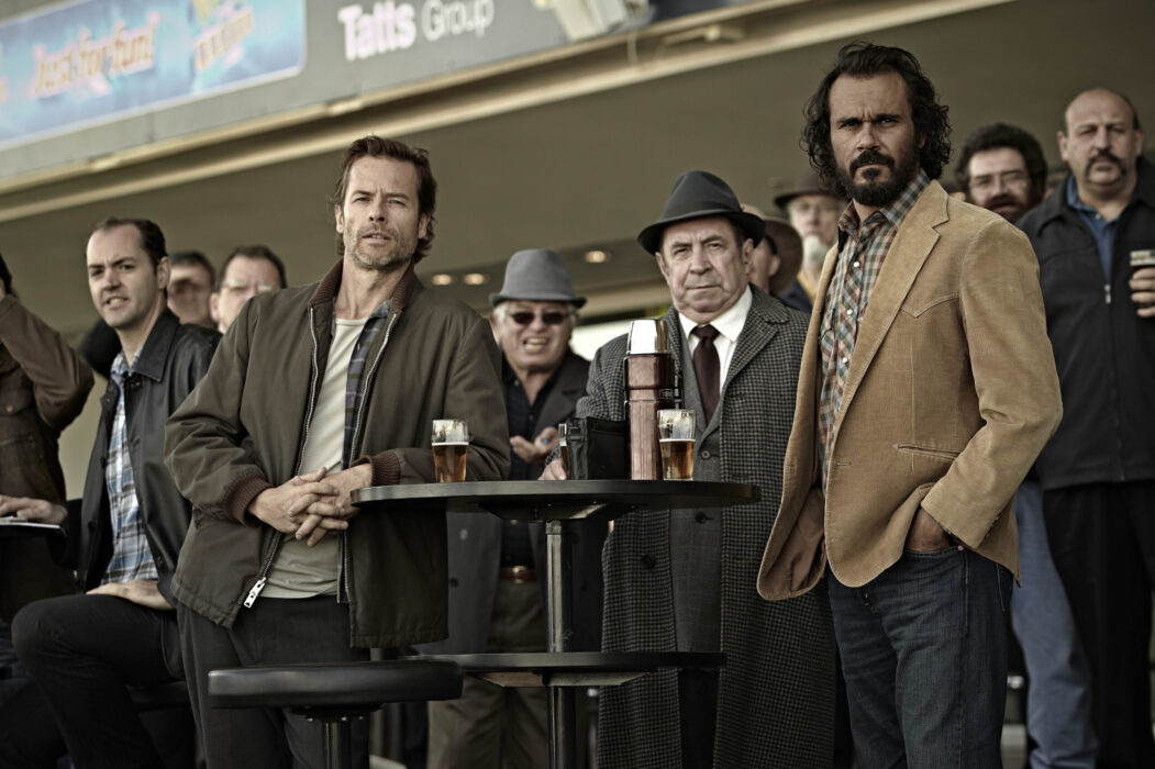 Jack Irish at the races, with Guy Pearce as Jack Irish, Roy Billing as Harry Strang, and Aaron Pedersen as Cam Delray