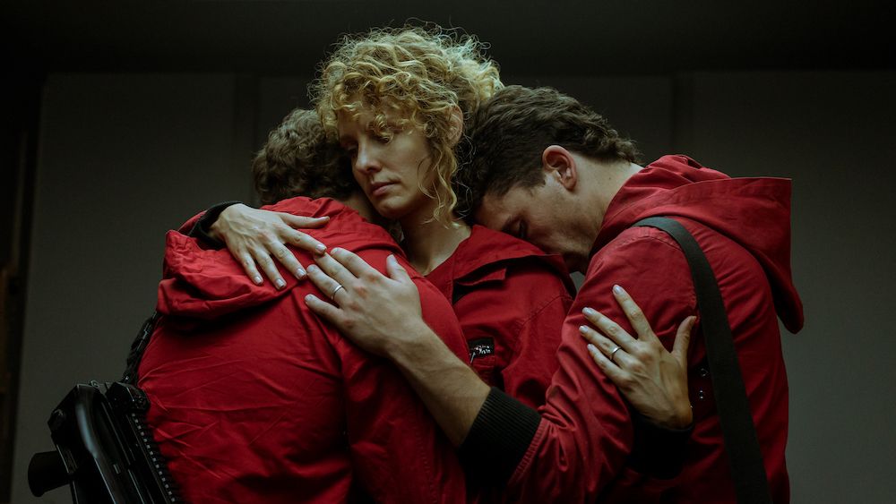 Money Heist shot of characters hugging. Miguel Herrán as Río, Esther Acebo as Mónica, and Jaime Lorrente as Denver.